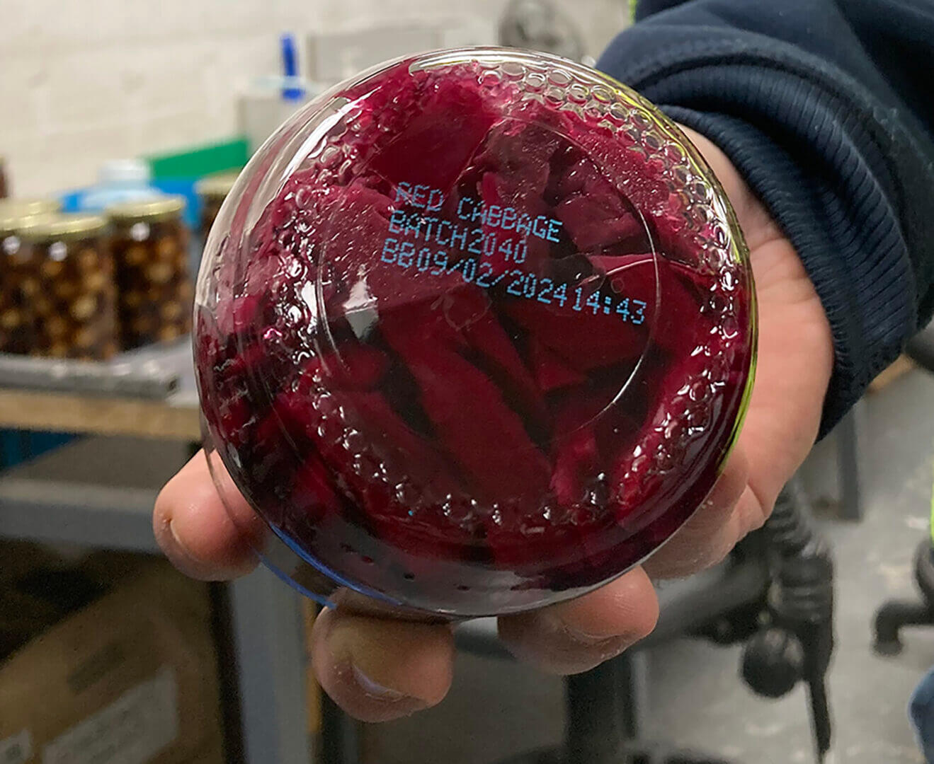 Jar of red cabbage in a hand.